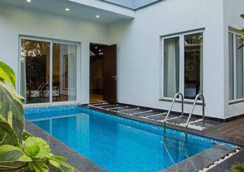 a swimming pool in front of a house at Villa Esencia by VEO - Part of StayVista in Siolim