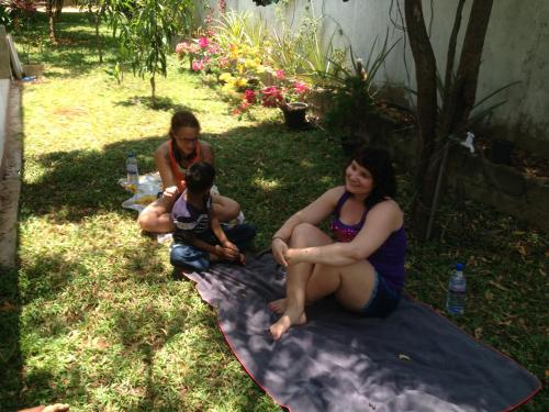 a group of people sitting on a blanket in the grass at Disna Homestay in Habarana