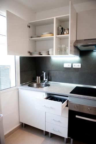a kitchen with white cabinets and a sink at Villa SCIROCCO Madeira - Ocean View in Machico