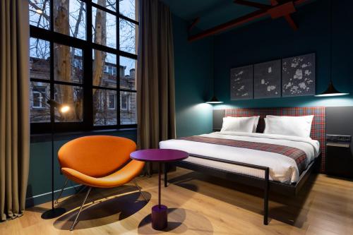 um quarto com uma cama, uma cadeira e uma janela em Hotel Zeg em Tbilisi