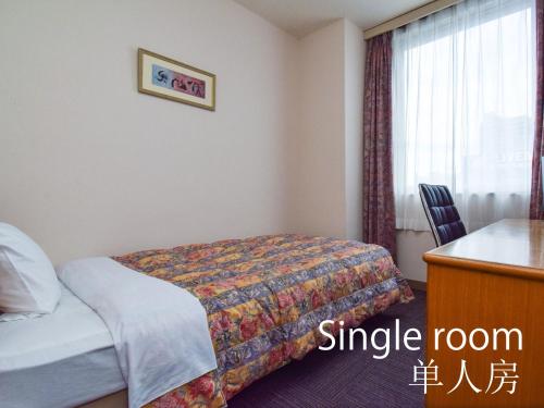 a bedroom with a bed and a desk at Hotel Maira in Okayama