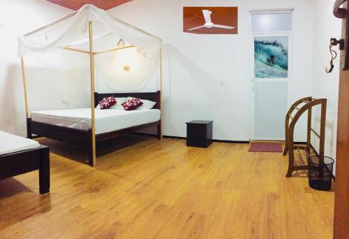1 dormitorio con cama con dosel y suelo de madera en De Perla Resort, en Arugam Bay