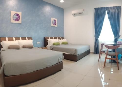a bedroom with two beds and a table and a chair at Austin GuestHouse in Ipoh
