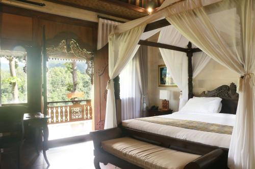 a bedroom with a canopy bed and a window at Shanti Natural Panorama View Hotel in Singaraja