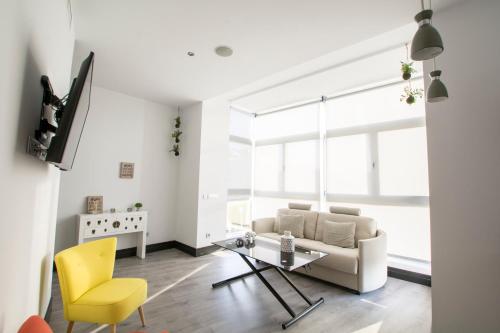 sala de estar con sofá, mesa y silla amarilla en Apartamentos Avenue Rooms, en Málaga