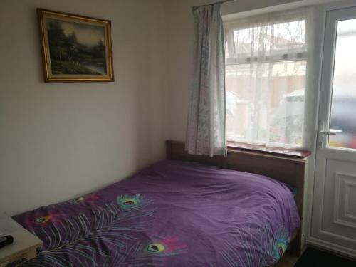 1 dormitorio con cama morada frente a una ventana en Rest room near to Heathrow Airport en Ashford