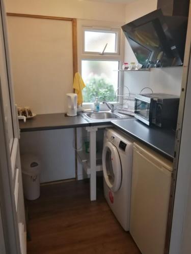 een keuken met een wastafel en een wasmachine bij Rest room near to Heathrow Airport in Ashford
