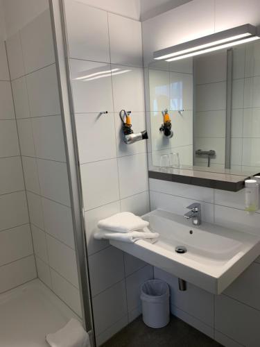 Hotel Maxplatz في هوف: حمام أبيض مع حوض ومرآة