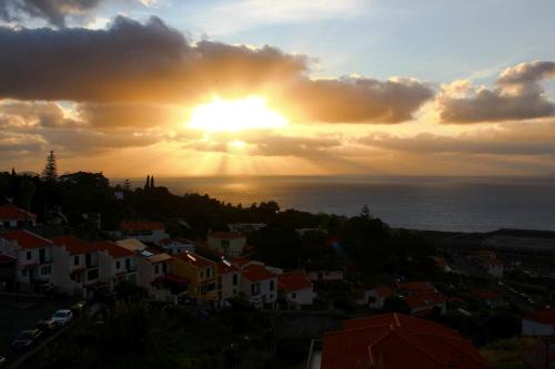 a sunset over a city with houses and the ocean at Villa SCIROCCO Madeira - Ocean View in Machico