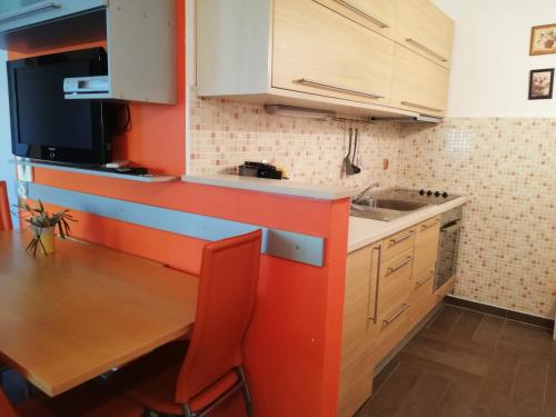 una cocina con armarios naranjas y blancos y una mesa de madera. en Apartment Adriana, en Povljana