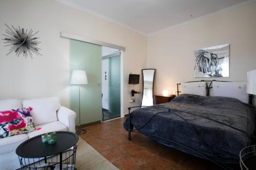 ein Schlafzimmer mit einem Bett, einem Sofa und einem Tisch in der Unterkunft Romantic and cosy apartment in Athen