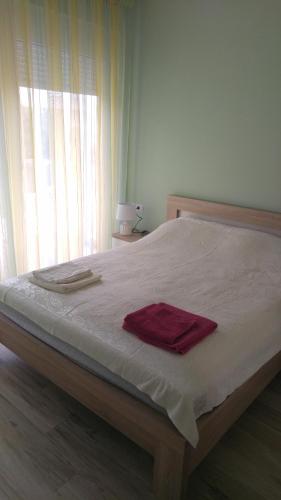 a bed with a red towel on it with a window at Your Home Montenegro in Dobra Voda