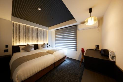 a bedroom with a bed and a desk and a window at Rinn Kamiebisu in Kyoto
