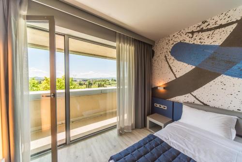a bedroom with a bed and a large window at JR Hotels Gigli Firenze in Calenzano