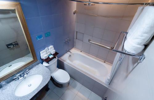 a bathroom with a tub and a toilet and a sink at Microtel by Wyndham General Santos in General Santos