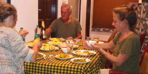 a group of people sitting around a table eating food at Marari Lotus Beach Villa in Mararikulam