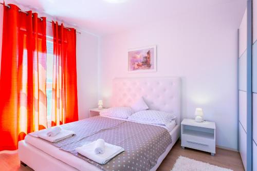 a bedroom with a pink bed and red curtains at Samir in Medulin