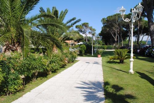 a walkway in a park with palm trees and a street light at Hotel Holiday Sul Lago in Bolsena