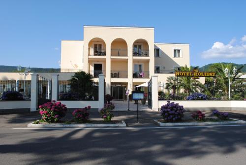 a white building with flowers in front of it at Hotel Holiday Sul Lago in Bolsena