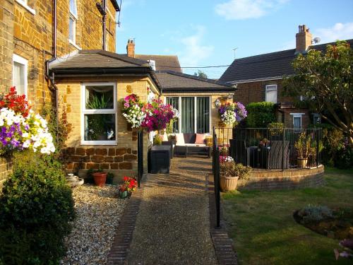 a garden with flowers and a house at Gate Lodge Guest House in Hunstanton