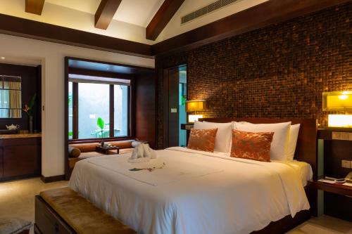 a bedroom with a large white bed with a brick wall at Narada Resort & Spa Perfume Bay Sanya - All Villas in Lingshui