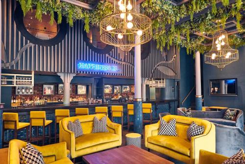 a restaurant with yellow chairs and a bar at Malmaison Belfast in Belfast