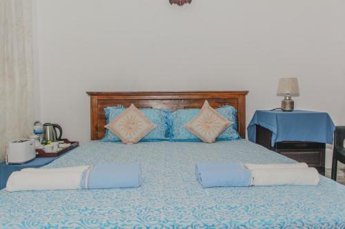 a large bed with blue and pink pillows on it at The Alexis's Guest House in Negombo