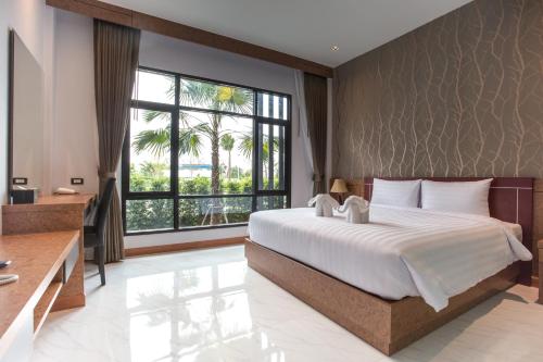 a bedroom with a large bed and a large window at Eireann Boutique Hotel in Prakhon Chai