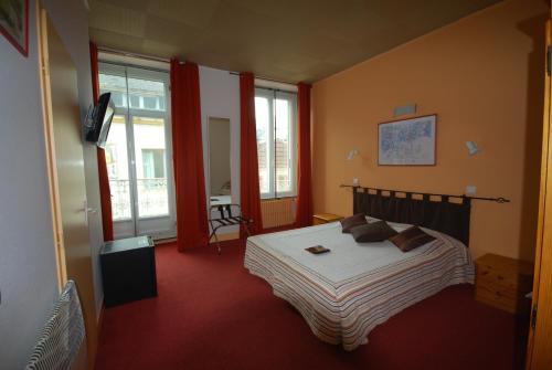 sypialnia z łóżkiem w pokoju z oknami w obiekcie Hôtel Adour w mieście Pau