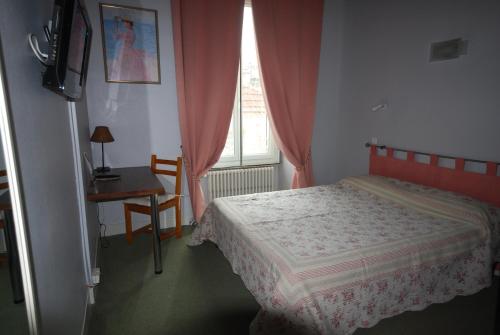 a bedroom with a bed and a desk and a window at Hôtel Adour in Pau