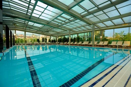 a large swimming pool with a large glass ceiling at Grand Ankara Hotel Convention Center in Ankara