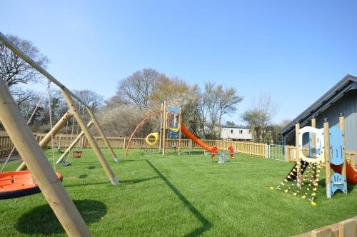 a park with a playground with a slide and swings at Camping Pods, Carlton Meres Holiday Park in Rendham