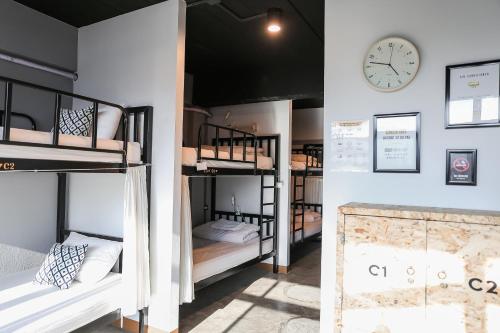 een groep stapelbedden in een kamer met een klok bij Jeune Hostel Chiang Mai - Chang Phuak in Chiang Mai
