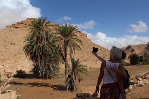 a woman taking a picture of a desert with a camera at Auberge Alferdaous in Tataouine