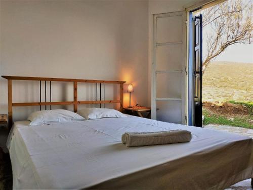 a bed in a bedroom with a large window at Vitali Beach Houses in Andros