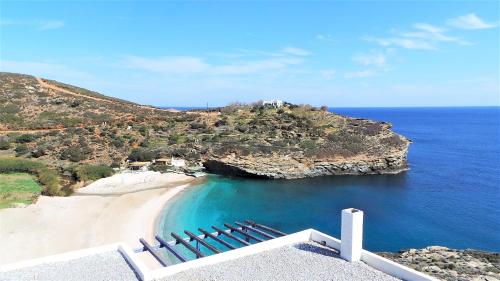 a group of chairs on a beach next to the ocean at Vitali Beach Houses in Andros