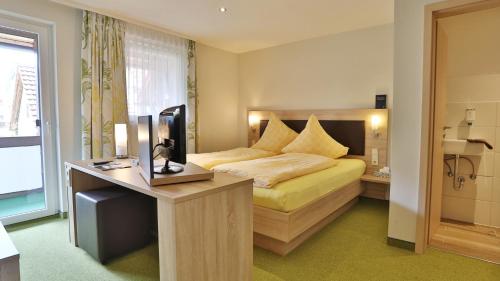 Hotel KRONE Garni في Deckenpfronn: غرفة نوم بسرير ومكتب مع تلفزيون