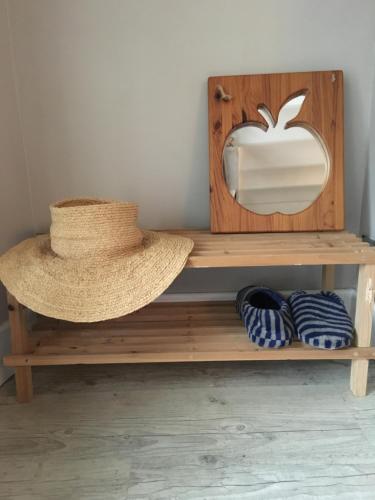 un chapeau assis sur une étagère en bois avec un miroir de pomme dans l'établissement Le Gîte de Pomme, à Nargis
