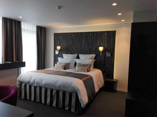 ein Hotelzimmer mit einem großen Bett mit Kissen in der Unterkunft Hotel Royal in De Panne