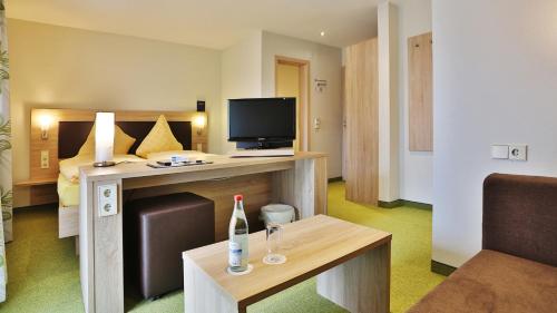 a hotel room with a bed and a television at Hotel KRONE Garni in Deckenpfronn