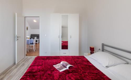ein Schlafzimmer mit einem Bett mit einem Buch auf einem roten Teppich in der Unterkunft Red Wine Apartment in Dubrovnik