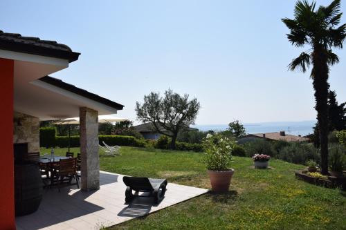 a patio with a table and chairs and a palm tree at Lovely villa Elena - Garda Lake in Bardolino