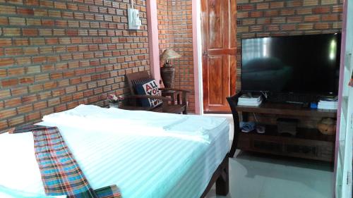 a bedroom with a bed and a tv and a brick wall at Sun smile(cafe & homestay) in Ubon Ratchathani