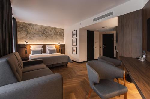 um quarto de hotel com uma cama, um sofá e cadeiras em Dvor Podznoeva Studios and Apartments em Pskov