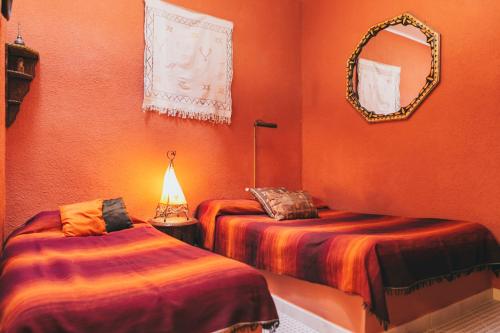 Habitación con 2 camas y espejo en la pared. en El Riad Andaluz, en Málaga