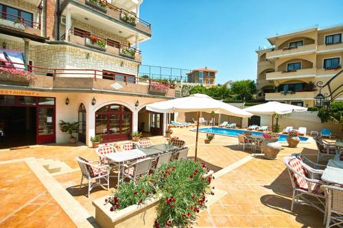 een patio met tafels en stoelen en een zwembad bij Hotel Kleopatra in Ulcinj