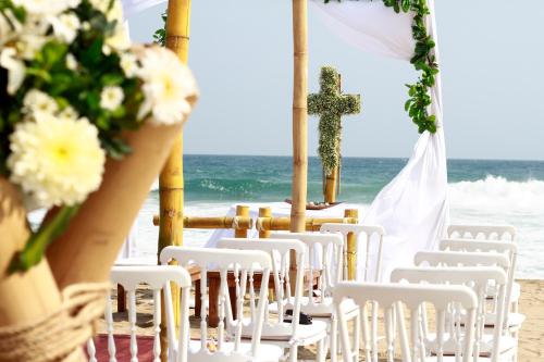 a wedding ceremony on the beach with white chairs and a cross at Hotel Nude Zipolite & beach club in Zipolite