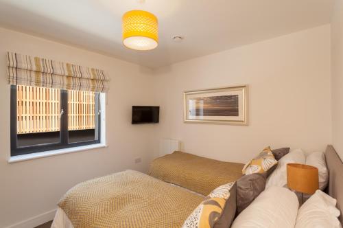 a living room with a couch and a window at 8 Woolacombe West - Luxury Apartment at Byron Woolacombe, only 4 minute walk to Woolacombe Beach! in Woolacombe
