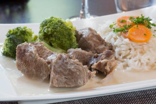 a plate of food with meat and broccoli and rice at The Originals City, Hôtel et Restaurant Aster, Saint-Avold Nord in Creutzwald-la-Croix
