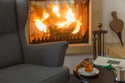 a chair and a table with a fire in a fireplace at The Originals City, Hôtel et Restaurant Aster, Saint-Avold Nord in Creutzwald-la-Croix